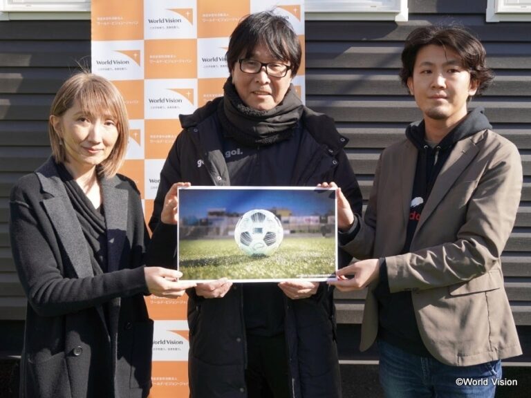 高橋陽一先生（中央）、dounle jump.tokyo株式会社代表取締役CTO満足亮さま（右）、 ワールド・ビジョン・ジャパン事務局長木内真理子（左）限定デザインのサッカーボールのイメージとともに